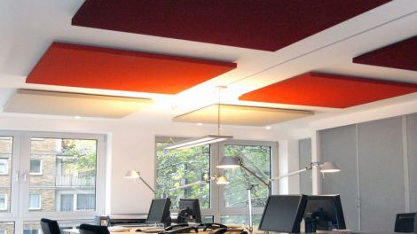 Mehrere rote Schallabsorber an Decke über Büroarbeitsplätzen.